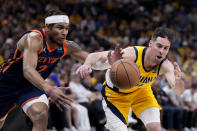 New York Knicks guard Miles McBride (2) fights for a loose ball with Indiana Pacers guard T.J. McConnell, right, during the second half of Game 4 in an NBA basketball second-round playoff series, Sunday, May 12, 2024, in Indianapolis. (AP Photo/Michael Conroy)