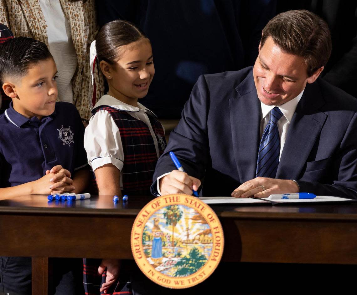 Florida Governor Ron DeSantis signs a bill to expand school vouchers across Florida during a press conference at Christopher Columbus High School on Monday, March 27, 2023, in Miami, Fla.