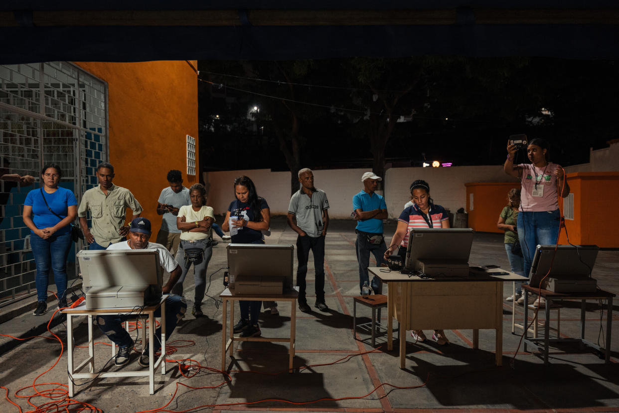 Trabajadores de un centro de votación en Petare, Venezuela, se desplazaron al exterior al enfrentarse a problemas en la transmisión de los votos durante la votación del domingo. (Adriana Loureiro Fernandez/The New York Times)