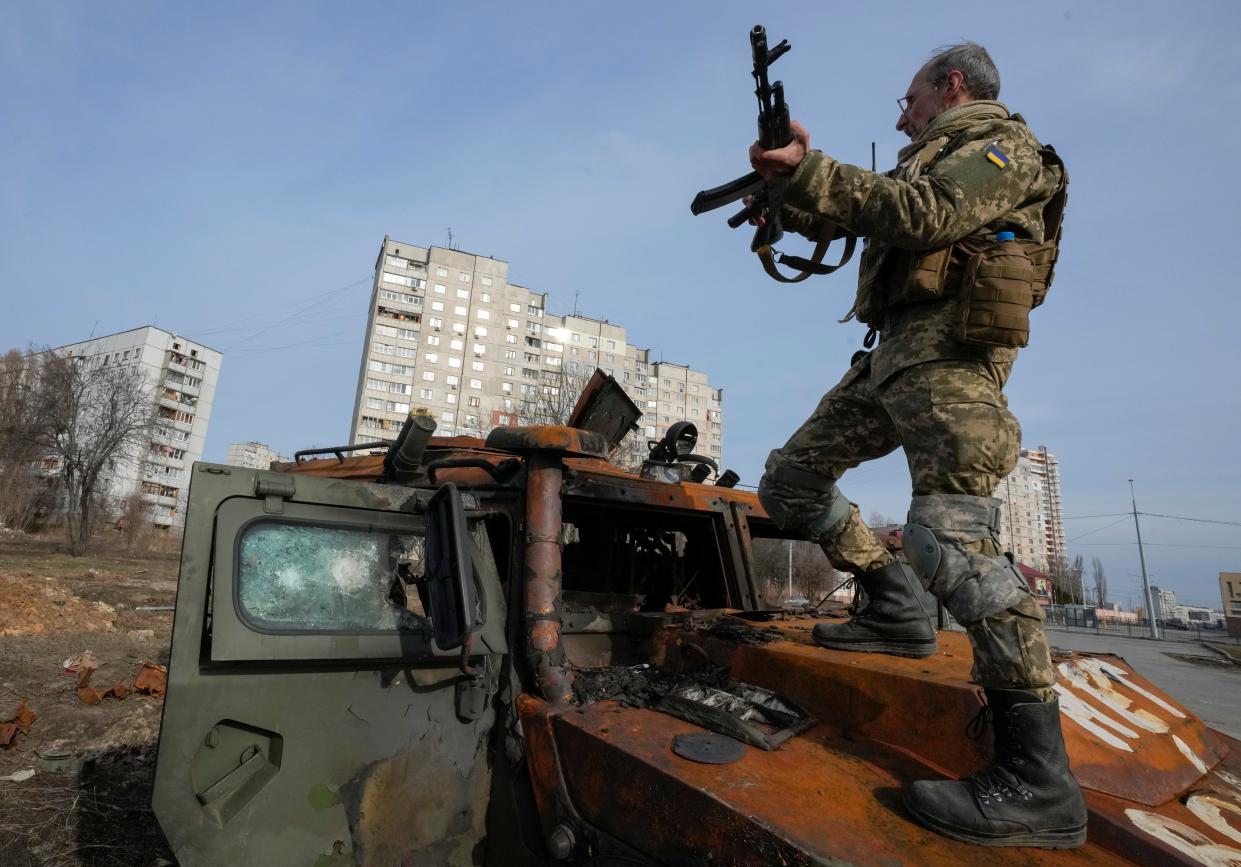 A Ukrainian soldier stands a top a destroyed Russian APC after recent battle in Kharkiv, Ukraine, Saturday, March 26, 2022. 