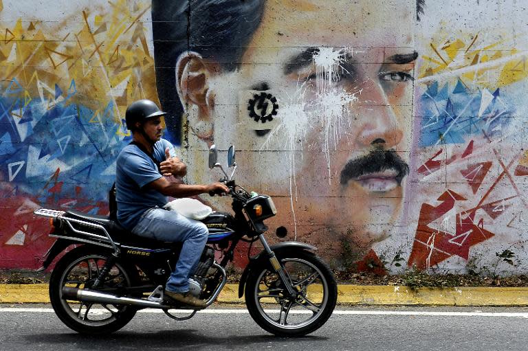 A motorcyclist passes by a graffiti depicting Venezuelan President Nicolas Maduro in Caracas on April 17, 2015