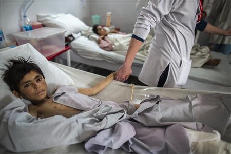 Nurse Nicole Burwood (C) holds the hand of Gullali, 10, who sustained bullets injuries, during a follow-up visit of patients at Emergency hospital in Kabul March 27, 2014. REUTERS/Zohra Bensemra