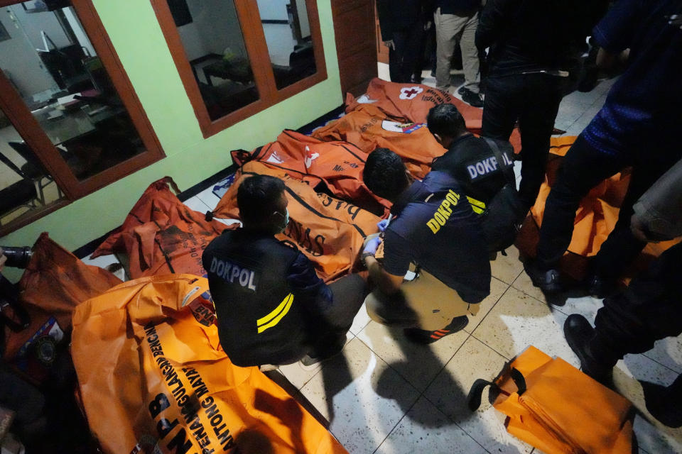 Indonesian police inspect body bags of victims after a fire broke out at a neighborhood in Jakarta, Indonesia, Friday, March 3, 2023. A large fire broke out at a fuel storage depot in Indonesia's capital on Friday, killing several people, injuring dozens of others and forcing the evacuation of thousands of nearby residents after spreading to their neighborhood, officials said. (AP Photo/Achmad Ibrahim)