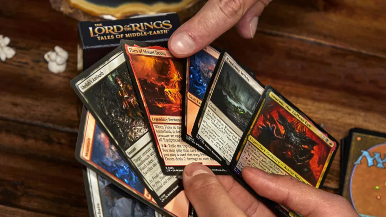  A hand points to Magic: The Gathering cards someone is holding. 