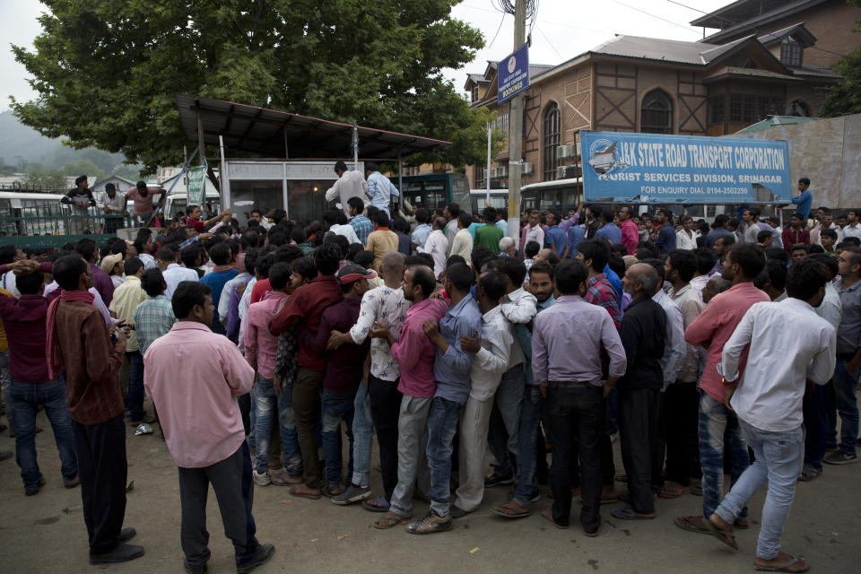 Indian migrant workers wait outside the government transport yard waiting to buy bus tickets to leave the region, during curfew in Srinagar, Indian controlled Kashmir, Wednesday, Aug. 7, 2019. Hit by a complete security lockdown in Kashmir, hundreds of poor migrant workers have begun fleeing the Himalayan region to return to their far-away villages in northern and eastern India. (AP Photo/ Dar Yasin)