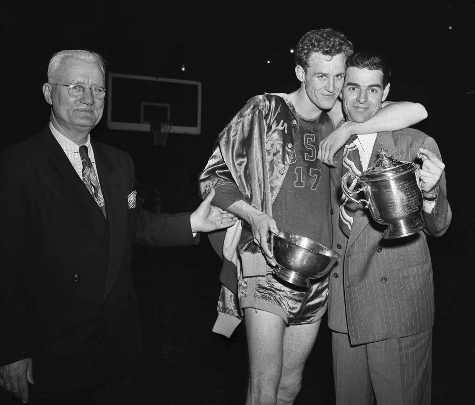 FILE - San Francisco forward Don Lofgran, center, and Pete Newell, coach of the University of San Francisco basketball team, embrace after San Francisco won the National Invitation Basketball tournament at Madison Square Garden in New York, March 19, 1949. San Francisco defeated Loyola of Chicago 48-47. Lofgran holds the trophy awarded him as most valuable player and Newell the Kelleher Memorial Trophy as coach of the winning team. Person at left is unidentified. (AP Photo/Marty Lederhandler, File)