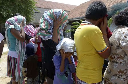 Sri Lankan asylum seekers who were sent back by Australia cover their faces as they wait to enter a magistrate's court in the southern port district of Galle July 8, 2014. REUTERS/Stringer