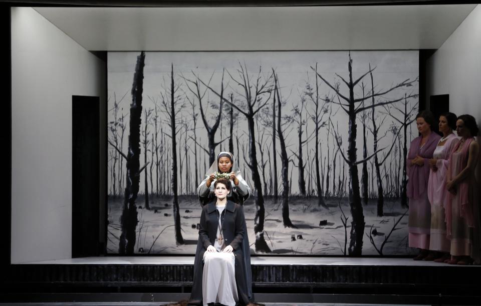 In this picture taken Friday, June 21, 2013, Anja Harteros in the role of Leonora, front, sings during a dress rehearsal for the opera "Il Trovatore" by Giuseppe Verdi in the Bavarian State Opera House in Munich, southern Germany. This wild new production by Olivier Py opened the company's annual Munich Opera Festival. It's a non-stop barrage of nightmarish images mixing styles and periods that assault the audience at lightning speed on a multi-tiered revolving set. (AP Photo/Matthias Schrader)