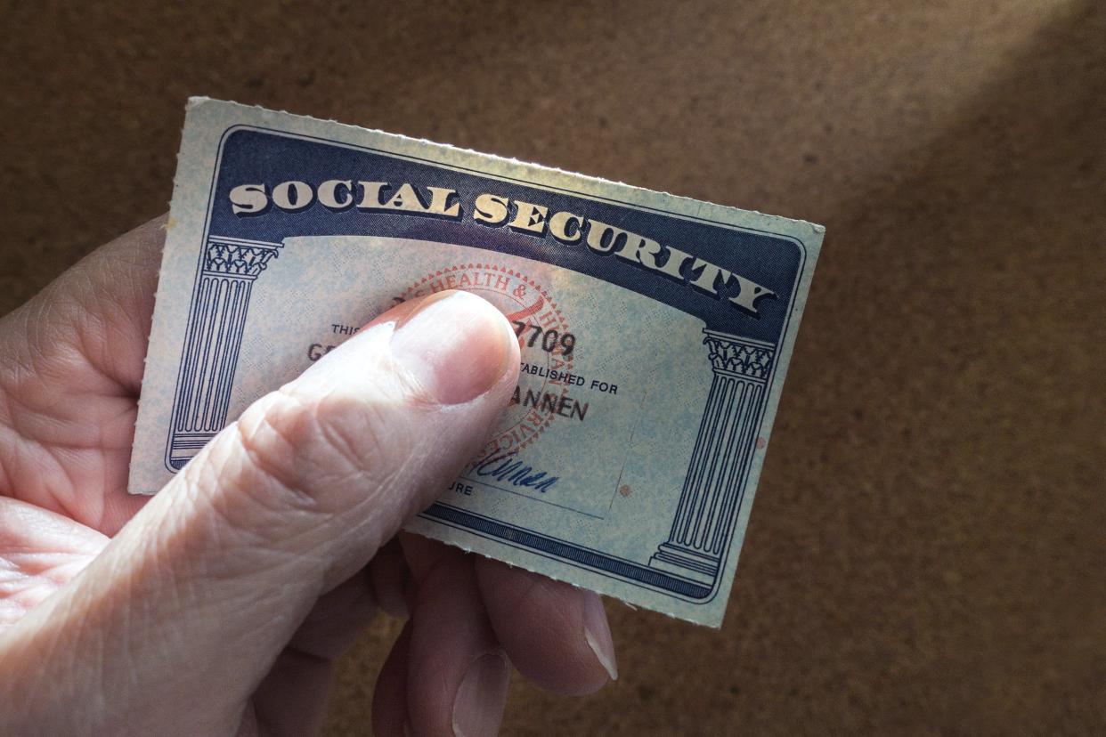 Hand holding social security card with thumb over the number