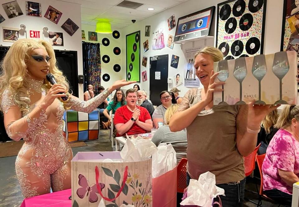 Amanda Everett of New Philadelphia hoists a prize at drag bingo at That Pop Up Bar at Twisted Citrus restaurant in North Canton, while drag queen Anhedonia Delight looks on.