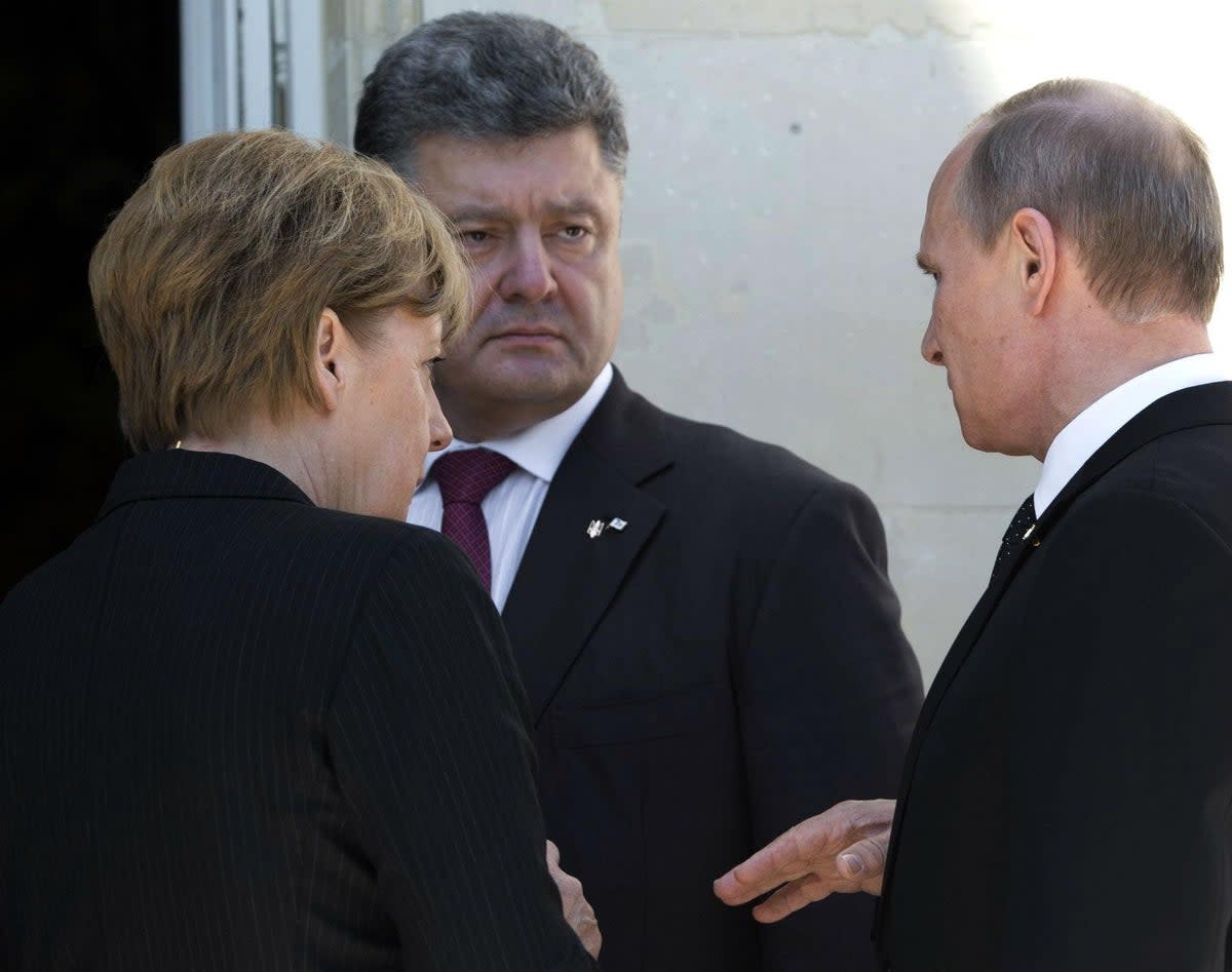 Former German chancellor Angela Merkel mediates a tense meeting between then-Ukrainian president Petro Poroshenko and Vladimir Putin at a D-Day commemoration in 2014 (AP)