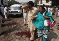 A man and woman mourn the death of their relatives at the site of a blast at a church in Peshawar September 22, 2013. A pair of suicide bombers blew themselves up outside the church in the Pakistani city of Peshawar, killing 40 people after Sunday mass, security officials said. REUTERS/Fayaz Aziz (PAKISTAN - Tags: RELIGION CIVIL UNREST)