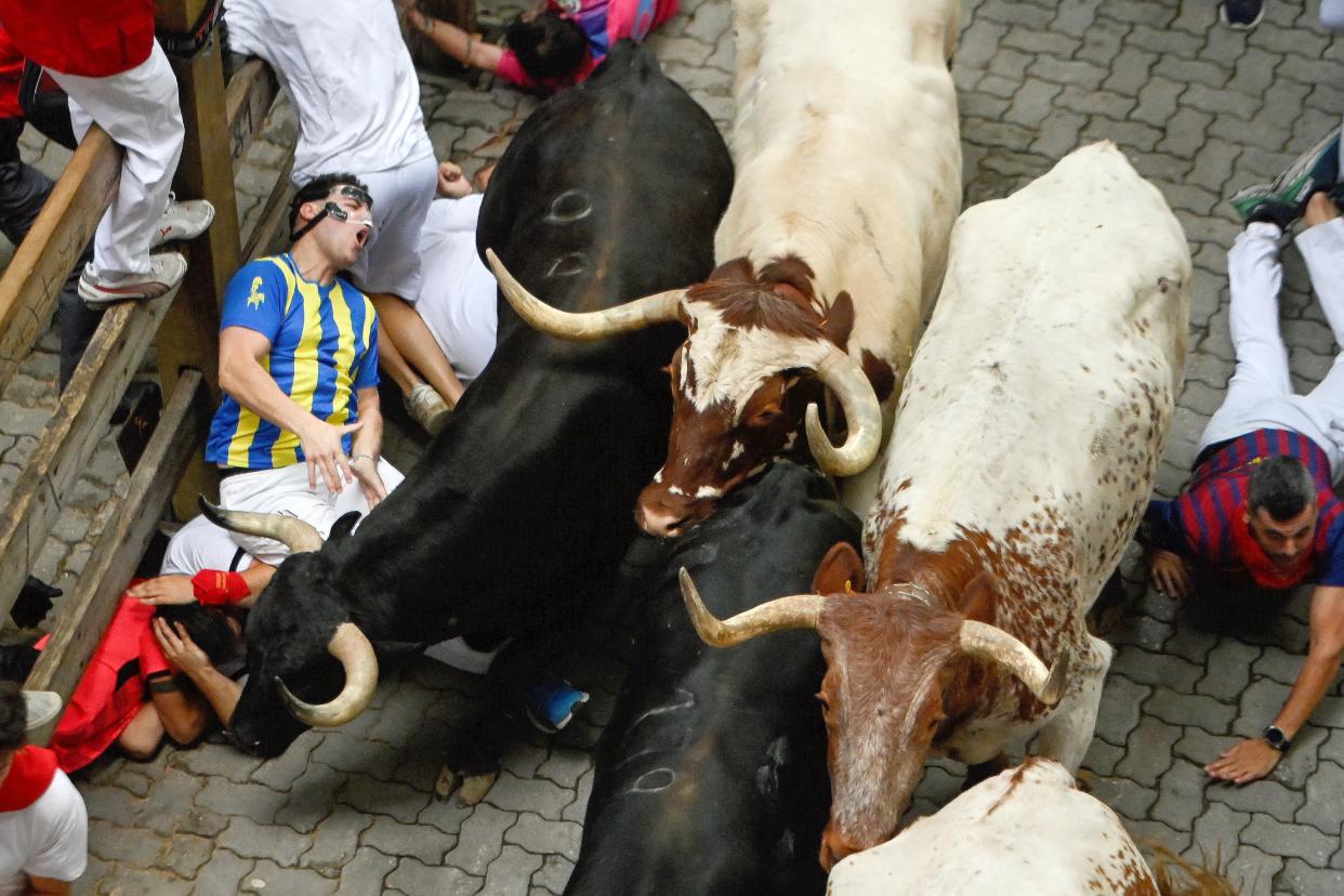 Participants fall on the street while running ahead of the bulls.