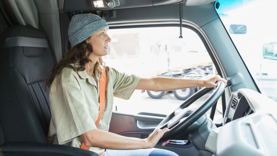 A mature woman driving a semi-truck.