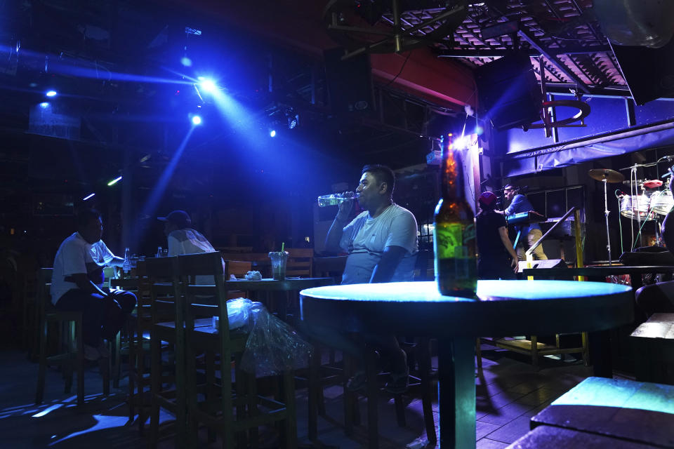 Customers drink beers at a bar along the "costera," the seaside boulevard that runs through the hotel zone, in the aftermath of Hurricane Otis, in Acapulco, Mexico, Saturday, Nov. 11, 2023. (AP Photo/Marco Ugarte)