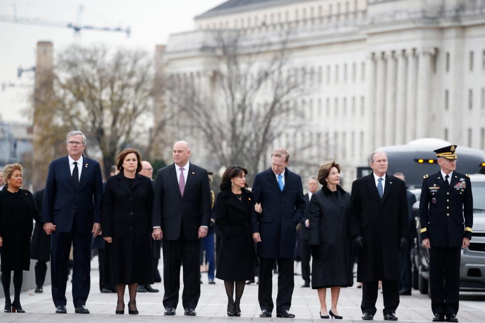 From right, former President George W. Bush, second from right, former first lady Laura Bush, Neil Bush, Sharon Bush, Bobby Koch, Doro Koch, Jeb Bush and Columba Bush, stand just prior to the flag-draped casket of former President George H.W. Bush being carried by a joint services military honor guard from the U.S. Capitol, Wednesday, Dec. 5, 2018, in Washington.