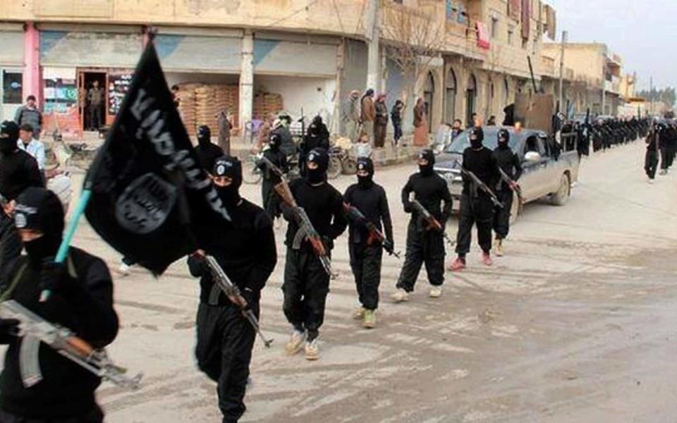 Armed Isil fighters march through Raqqa, Syria, in 2014 - AP