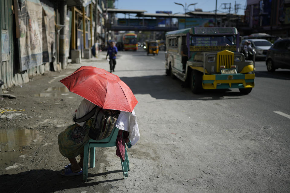 A street vendor uses an umbrella to protect her from the sun along a street in Manila, Philippines on Monday, April 29, 2024. Millions of students in all public schools across the Philippines were ordered to stay home Monday after authorities cancelled in-person classes for two days as an emergency step due to the scorching heat and a public transport strike. (AP Photo/Aaron Favila)