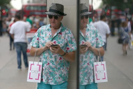 A shopper is reflected in the window of a store in London, Britain August 25, 2016. REUTERS/Neil Hall