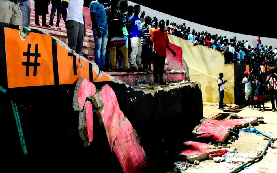 People stand before a collapsed wall at Demba Diop stadium  - Credit: Seyllou/AFP