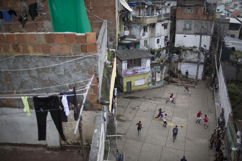 Neighbors and friends of the late Douglas Rafael da Silva Pereira play soccer in a plaza near the site where Silva Pereira's body was found in the Pavao Pavaozinho slum of Rio de Janeiro, Brazil, Wednesday, April 23, 2014. On Tuesday night, angry residents blaming police for his death set fires and showered homemade explosives and glass bottles onto a busy avenue in the city's main tourist zone following the killing of the popular local figure. (AP Photo/Felipe Dana)