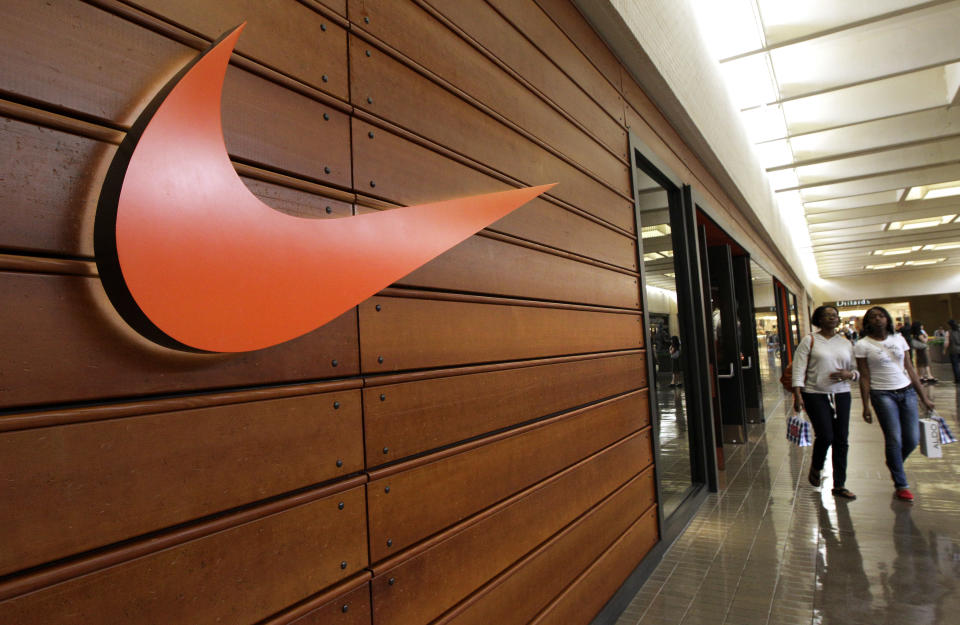 The NIKE symbol hangs on the wall near the entrance to the NIKE department store at the North Park Mall as customers exit the store Monday, March 19, 2012 in Dallas.  (AP Photo/Tony Gutierrez)