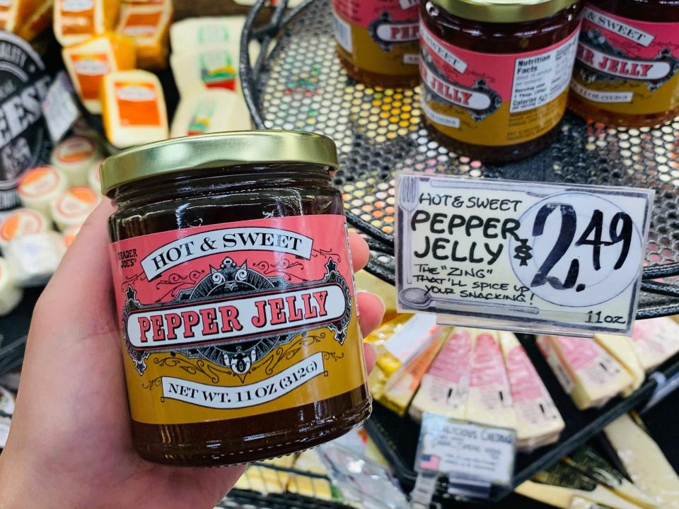 hand holding jar of trader joe's pepper jelly in cheese section