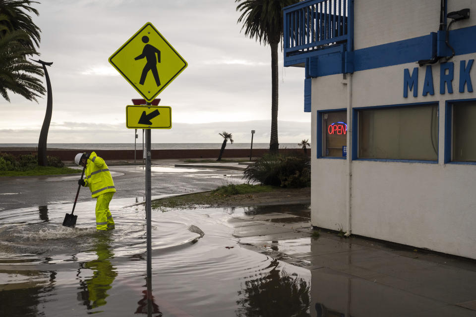 A Santa Cruz County public works employee clears a storm drain in the Rio Del Mar neighborhood of Aptos, Calif., Wednesday, Dec. 20, 2023 (AP Photo/Nic Coury)