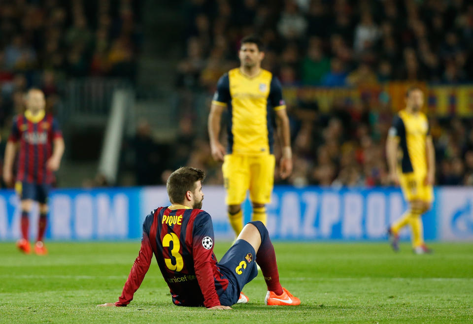 Barcelona's Gerard Pique sits on the pitch after injuring himself during a first leg quarterfinal Champions League soccer match between Barcelona and Atletico Madrid at the Camp Nou stadium in Barcelona, Spain, Tuesday April 1, 2014. Pique had to be substituted. (AP Photo/Emilio Morenatti)