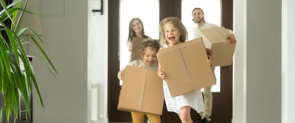 Happy family with kids bought new home, excited children funny girl and boy holding boxes running into big modern house.