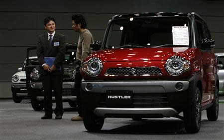 A visitor talks with a staff of Suzuki Motor Corp next to the new boxy minicars "Hustler" during its unveiling event in Tokyo December 24, 2013. REUTERS/Yuya Shino