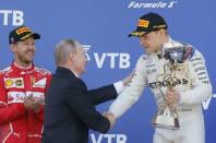 Formula One - F1 - Russian Grand Prix - Sochi, Russia - 30/04/17 - Russian President Vladimir Putin congratulates winner and Mercedes Formula One driver Valtteri Bottas of Finland as second-placed Ferrari Formula One driver Sebastian Vettel of Germany stands nearby on the podium. REUTERS/Maxim Shemetov