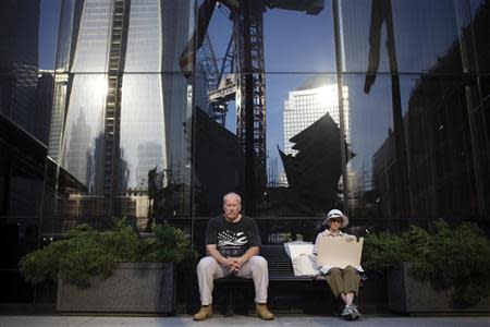 People sit before a moment of silence honoring the victims of the September 11 attacks outside the World Trade Center site in New York September 11, 2013. REUTERS/Shannon Stapleton