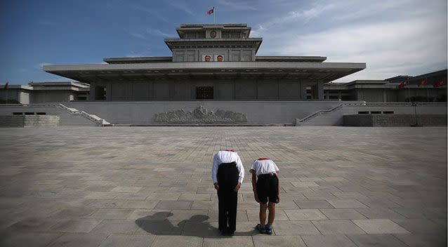 Two schoolchildren bow outside the Palace of the Sun. Source: AAP