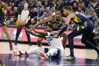 Minnesota Timberwolves guard Anthony Edwards (1) passes under pressure from Indiana Pacers forward Aaron Nesmith (23) and guard Tyrese Haliburton (0) during the second quarter of an NBA basketball game Wednesday, Dec. 7, 2022, in Minneapolis. (AP Photo/Andy Clayton-King)