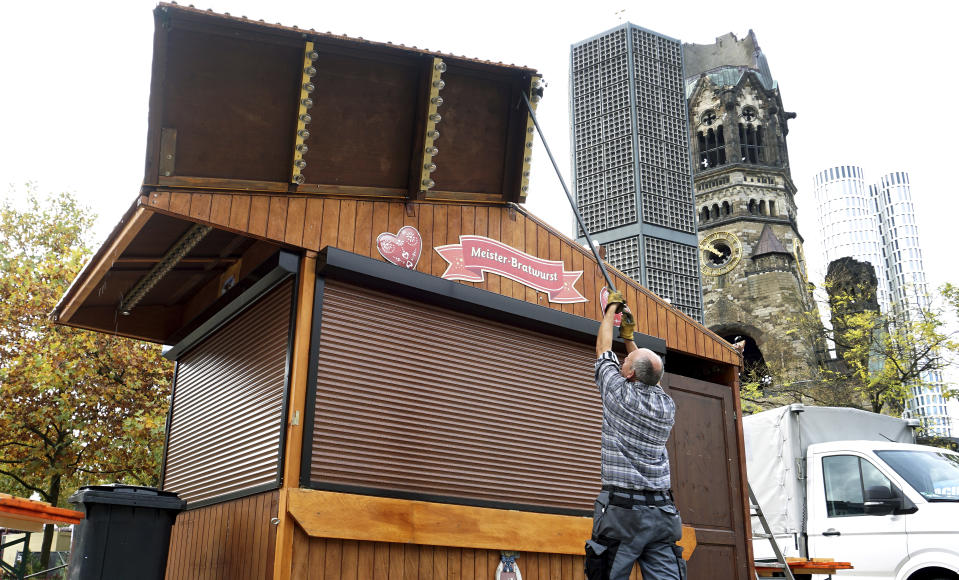 Due to the new coronavirus lockdown a Christmas market trader builds down a market booth at the Breitscheidt square close to the Kaiser Wilhelm Memorial Church, right, in Berlin, Germany, Monday, Nov. 2, 2020. (AP Photo/Michael Sohn)