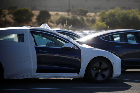 A partially wrapped Tesla Model 3 electric vehicle is seen at a lot in Richmond, California, U.S. June 22, 2018. Picture taken June 22, 2018. REUTERS/Stephen Lam