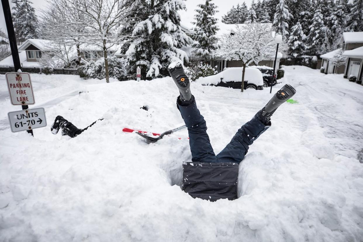 A kid digs a tunnel into a snow pile in Surrey, B.C., on Wednesday. Students in the city will get to enjoy a second snow day on Thursday. (Ben Nelms/CBC - image credit)