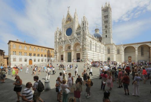 Tourists walk in the square in front of the Siena cathedral in August 2012. Magnificent Renaissance mosaics in the floor have been unveiled to give visitors a rare glimpse of scenes it took local artists 500 years to create