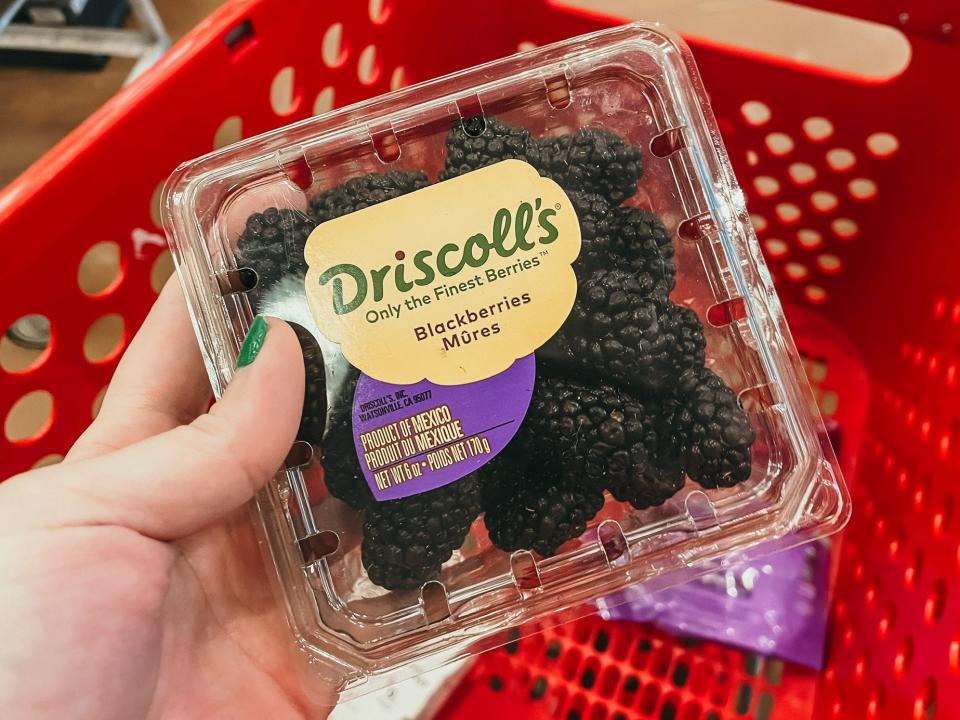 hand holding up a carton of driscolls blackberries at target