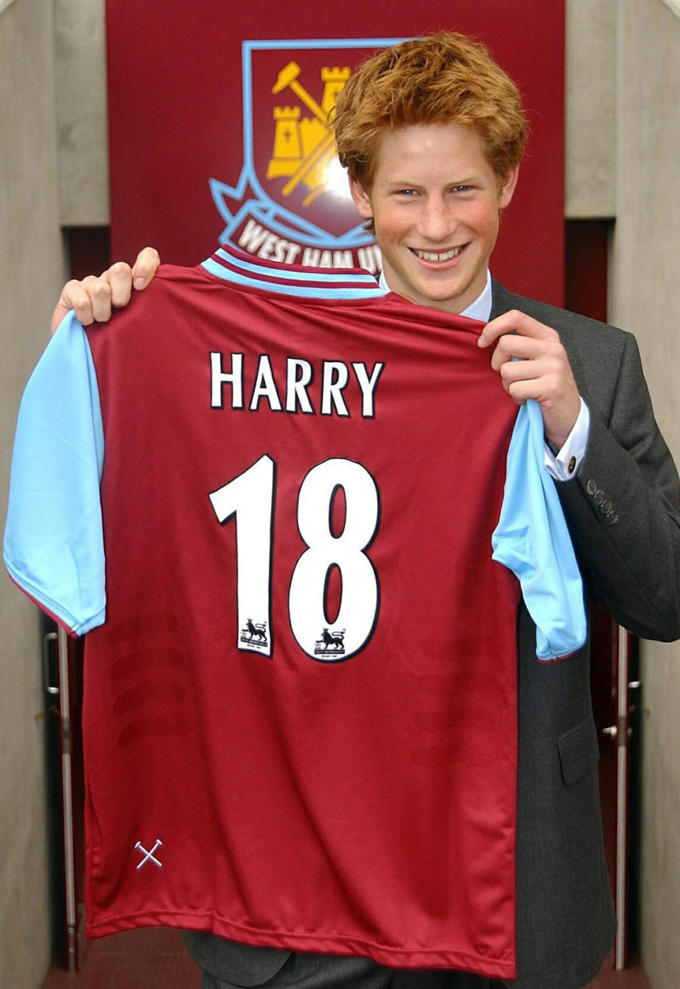 FILE - In this Thursday, Sept. 12, 2002 file photo, Britain's Prince Harry holds up a "birthday shirt", a soccer shirt of the English Premier League soccer club West Ham United at their Upton Park ground, in east London, three days prior to his 18th birthday. Princess Diana’s little boy, the devil-may-care red-haired prince with the charming smile is about to become a father. The arrival of the first child for Prince Harry and his wife Meghan will complete the transformation of Harry from troubled teen to family man, from source of concern to source of national pride. (Toby Melville/Pool Photo via AP, File)