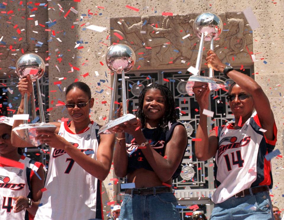 Houston Comets players Tina Thompson, left, Sheryl Swoopes, center, and Cynthia Cooper hoist the Comets' three WNBA championship trophies during a rally after a parade honoring the three-time WNBA champions Wednesday, Sept. 8, 1999, in Houston. (AP Photo/Brett Coomer)