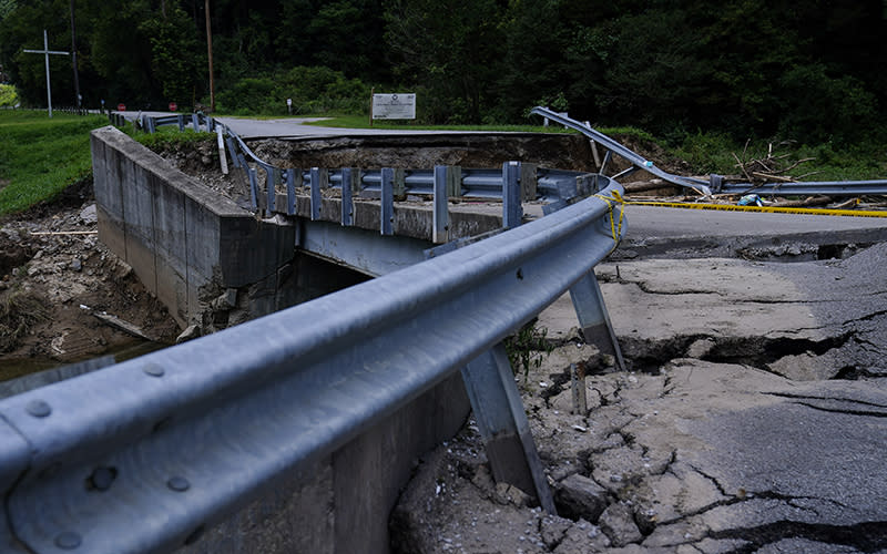 The road leading to a bridge above a creek cracks and breaks after massive flooding