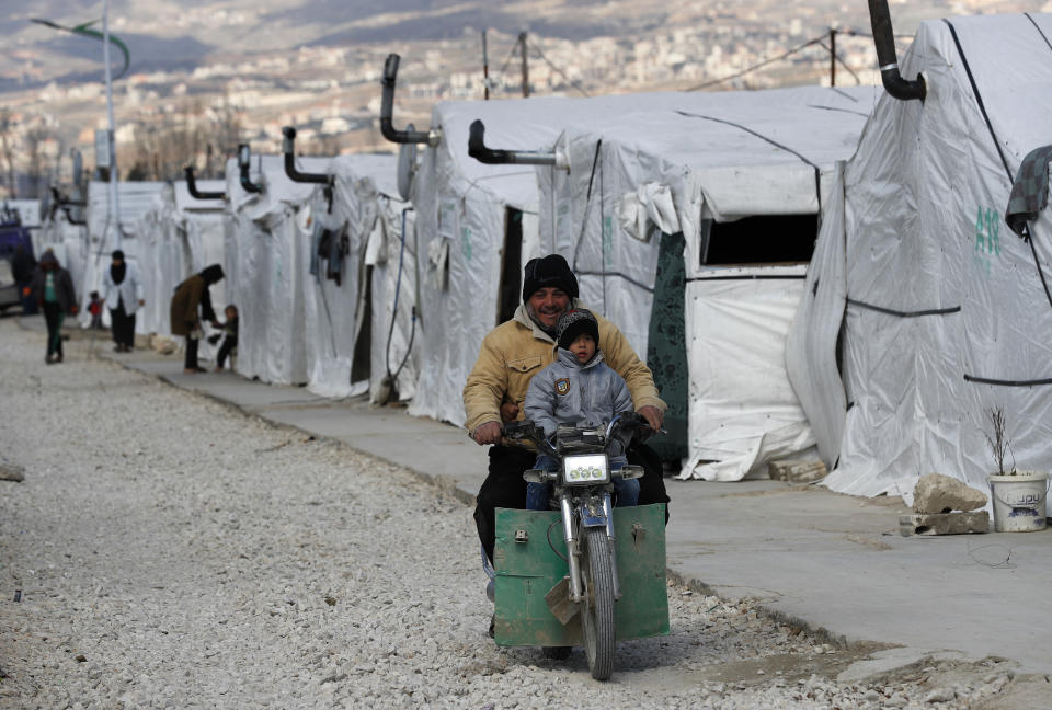 A Syrian displaced man and his son ride a motorcycle, as they drive between the tents at a refugee camp, in Bar Elias, in eastern Lebanon's Bekaa valley, Friday, March 5, 2021. Syria has been mired in civil war since 2011, after Syrians rose up against President Bashar Assad amid a wave of Arab Spring uprisings. Nearly ten years later, millions of displaced Syrians unlikely to return in the foreseeable future, even as they face deteriorating living conditions abroad. The Syrian conflict has resulted in the largest displacement crisis since World War II. (AP Photo/Hussein Malla)