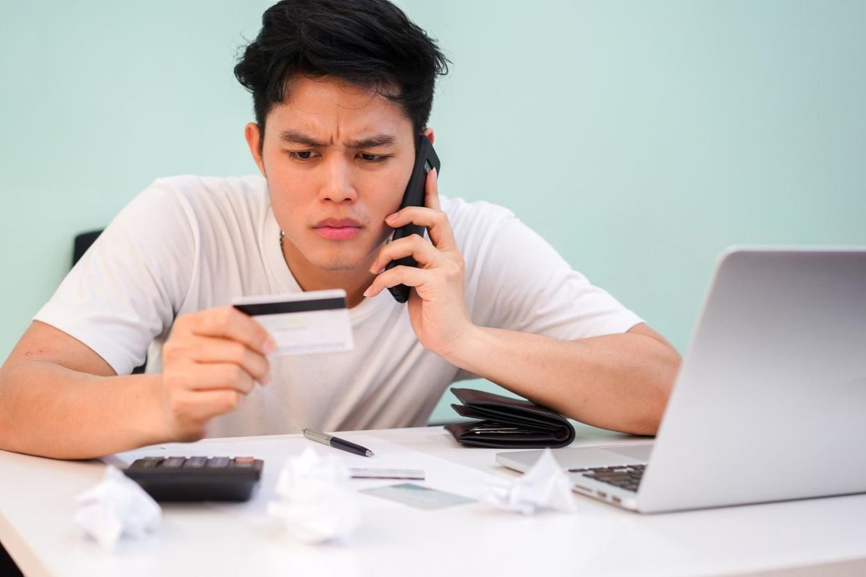 close up asian man using smartphone for calling to talk with banking operator for asking about payment (credit card monthly expense) on end of the month, financial risk or potential money scam