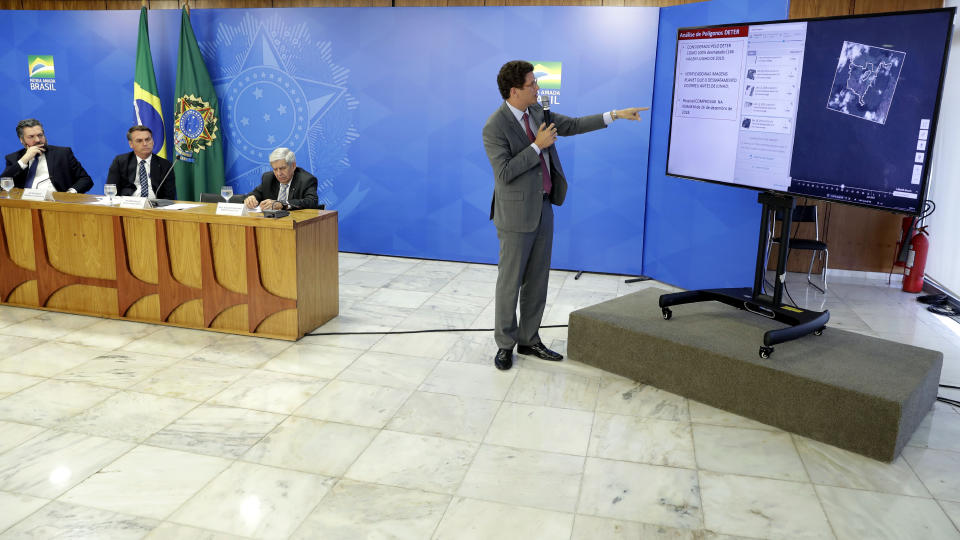 Brazil's Environment Minister Ricardo Salles gives a presentation during a press conference on deforestation in the Amazon at Planalto presidential palace, as President Jair Bolsonaro looks on, second from left, in Brasilia, Brazil, Thursday, Aug. 1, 2019. Bolsonaro is threatening to dismiss officers at the agency that monitors deforestation in the Amazon over its publication of data he disagrees with. (AP Photo/Eraldo Peres)