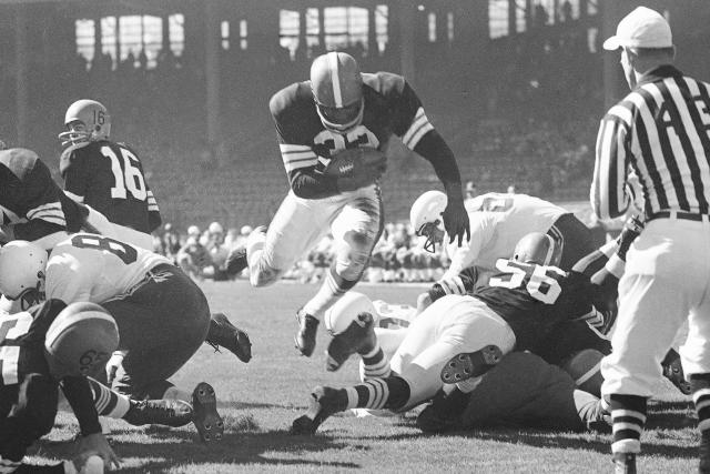 FILE - In this Dec. 8, 1953, file photo, Cleveland Browns coach Paul Brown  checks the protective mask of his quarterback Otto Graham. In 1950, the NFL  merged with the All-America Football