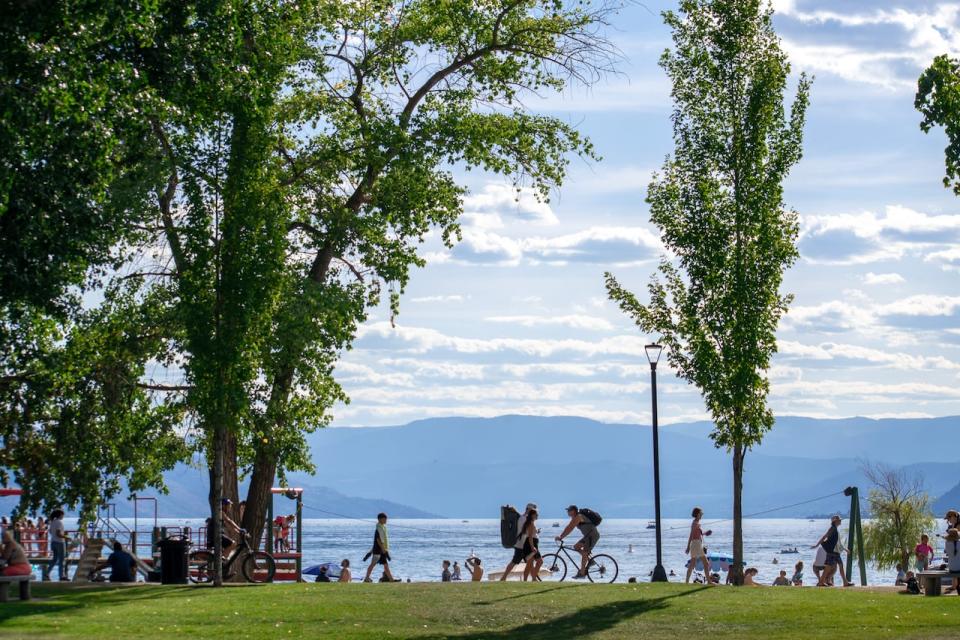 People walk on Boyce-Gyro Beach Park amid 30 C in Kelowna, B.C., on Aug. 12, 2023.