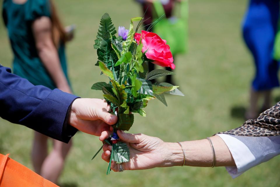 People hand out flower arrangements Thursday to be placed at Veterans Cemetery in Oklahoma City.