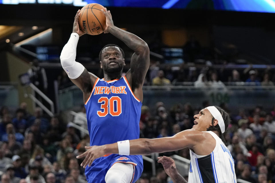 New York Knicks forward Julius Randle (30) looks to shoot over Orlando Magic forward Paolo Banchero, right, during the first half of an NBA basketball game, Friday, Dec. 29, 2023, in Orlando, Fla. (AP Photo/John Raoux)